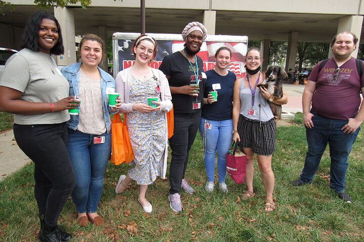 A smiling group of graduate students outside.